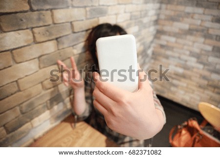 An Asian woman taking a cellphone self-shot.