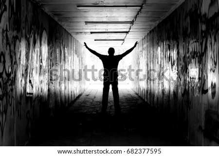A man in a tunnel with graffiti paintings on the wall - black and white version