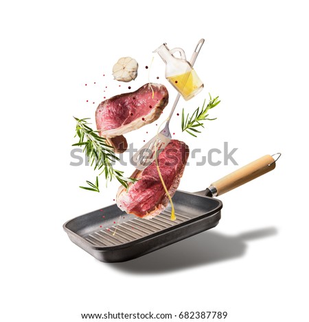 Flying raw beef steaks, with herbs, oil and spices with grill pan and kitchen utensils, isolated on white background, front view. Flying  food concept Royalty-Free Stock Photo #682387789