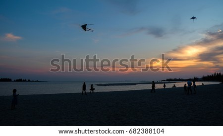 Silhouette of peoples at beach in Malacca, playing kites during sunset. The place is located at popular tourist site, Klebang, Malacca, Malaysia.