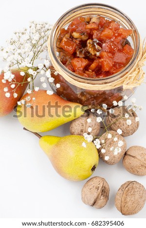 Pear jam with walnuts in a jar on a white background close-up.
