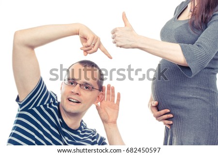 Father listening and showing belly of his pregnant wife, woman showing thumbs up, concept of extending family and expecting for newborn
