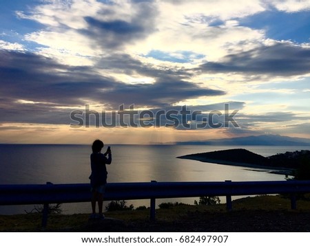 Silhouette of a girl taking photo of sunset