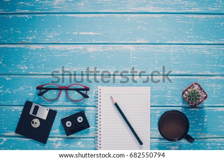 Top view casual lifestyle of work accessories on the vintage blue wood background, book, coffee, paper, glasses, pen and items objects on wooden, with copy space, Working desk table concept.