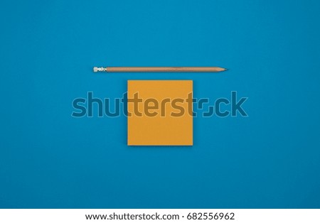 pencil and piece of paper on blue background