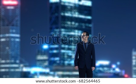 Young businessman standing with out of focus city skyscraper background . Night scene.