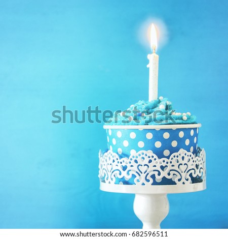 Birthday concept with cupcake and one candle on wooden table.