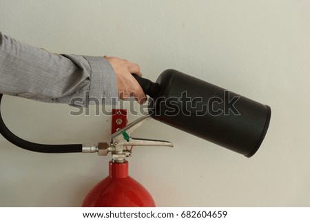 Close up a office man showing how to use fire extinguisher in building on white wall background.Hand holding extinguisher.