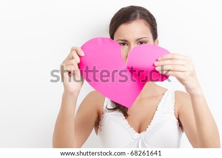 Young woman pulling pink paper heart to pieces.?