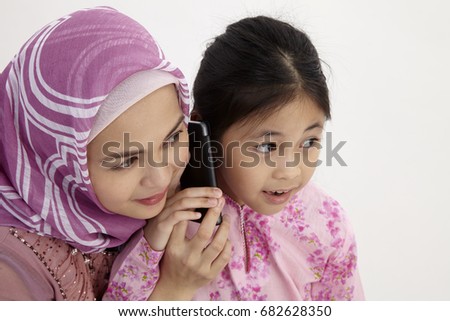 Closeup of excited girl and mother listening to cell phone