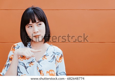 Portrait of young beautiful asian woman pointing to copyspace.