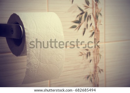 Toilet paper against the wall with tiles. Toned