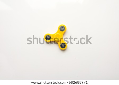 Yellow hand spiner. Stress relieving toy on white background. Close-up. Top view. Stock photo