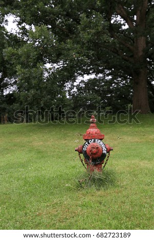 a fire hydrant on a green lawn with an out of service  sign attached.