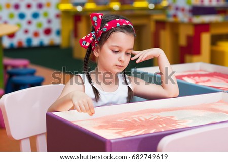 A little girl draws on sand, sand animation