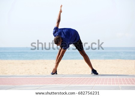 Full length portrait of young african man doing morning exercise on beach