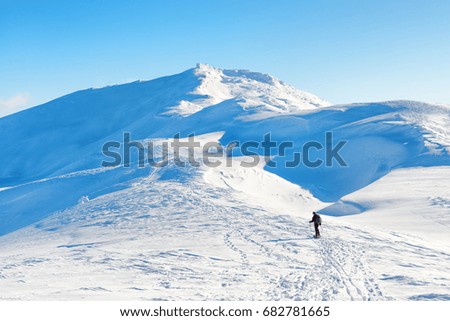 A man hiking in winter mountains with white snow on the peaks