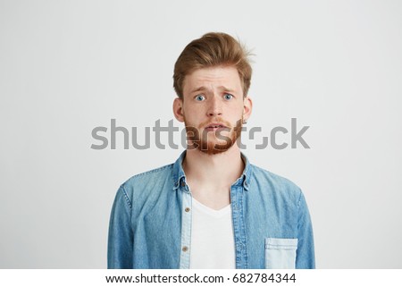 Young handsome guy looking at camera naively hopefully over white background. Royalty-Free Stock Photo #682784344