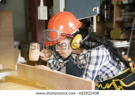 Asian pretty female carpenter Using wood hammer for wood.