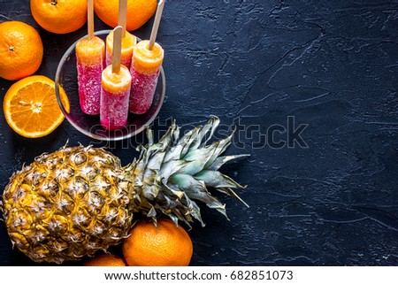 Fresh oranges, pineapple and citrus ice cream on black table background top view copyspace