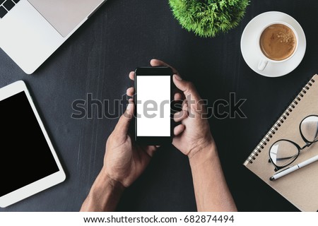 close-up on hand holding phone showing white screen on desk
