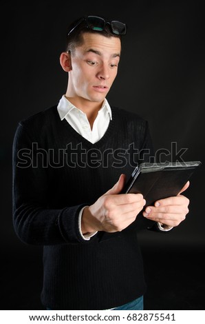 Surprised man looks at the tablet.