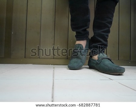 Young fashion man's legs in blue jeans and boots on floor