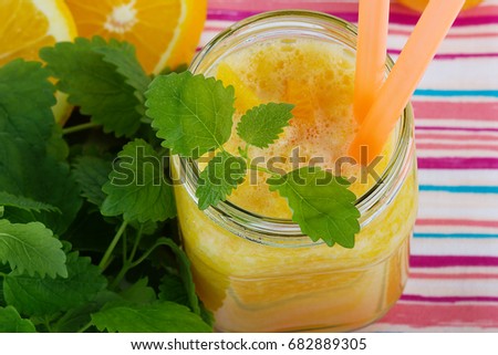 Smoothies from orange and tangerine with mint on a white wooden background