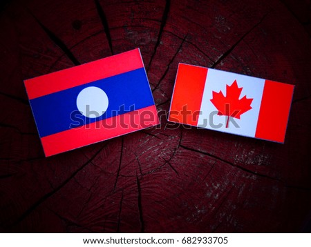Laos flag with Canadian flag on a tree stump isolated