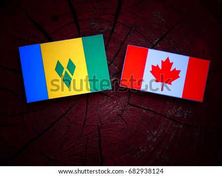 Saint Vincent and the Grenadines flag with Canadian flag on a tree stump isolated