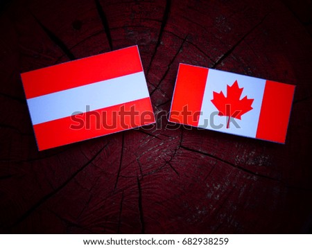 Austrian flag with Canadian flag on a tree stump isolated