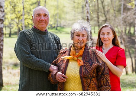 Photo of happy elderly couple and young caregiver 