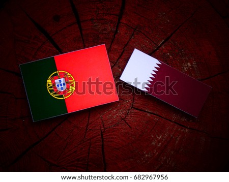 Portuguese flag with Qatari flag on a tree stump isolated