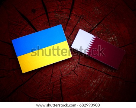 Ukraine flag with Qatari flag on a tree stump isolated