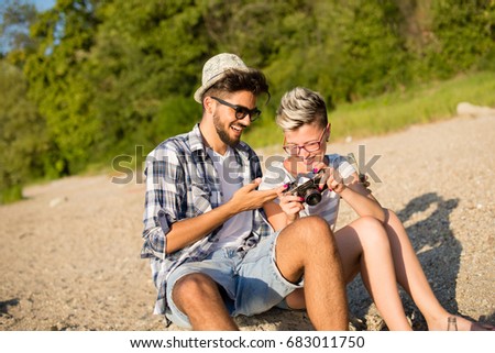 Young hipsters are taking pictures on beach, having a good time