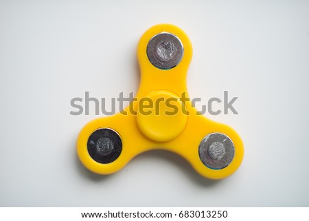 Yellow hand Spiner. Stress relieving toy on white background. Close-up. Top view. Stock photo