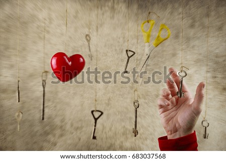 conceptual photo hand stretching for one of the many old vintage keys hanging on threads