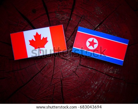 Canadian flag with North Korean flag on a tree stump isolated