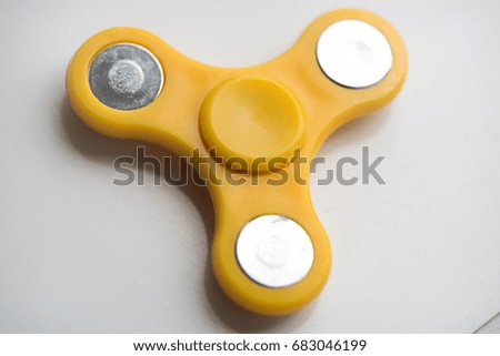 Yellow hand Spiner. Stress relieving toy on white background. Close-up. Top view. Stock photo