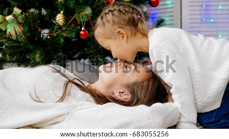 childhood, happiness, christmas, family and people concept - smiling little girl and mother hugging indoors