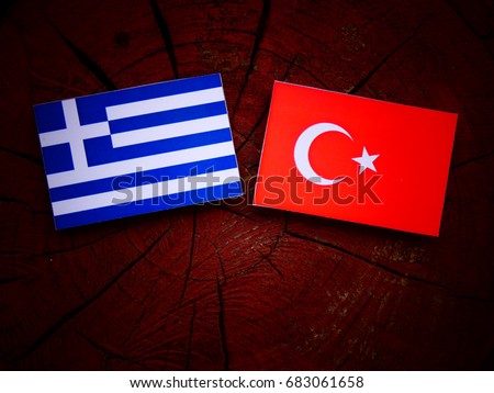 Greek flag with Turkish flag on a tree stump isolated