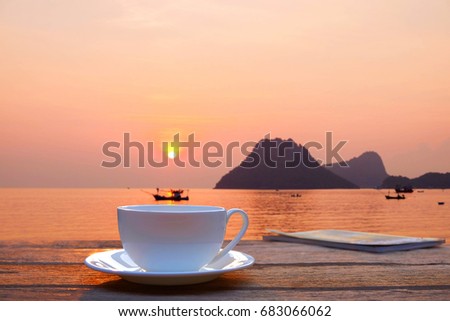 a selective focus picture of a cup of coffee on wooden table in the morning sunrise 