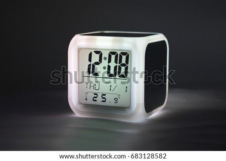 Modern alarm clock glowing light on dark backdrops and copyspace. LED light or digital display.