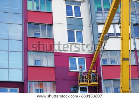 Man paints a house on a crane
