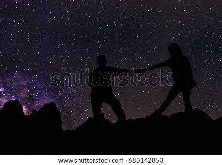 Silhouette of couple holding hands beneath the stars, Milky Way and a lot of stars over the mountain at Wadi Rum desert.  Sky at night, concept for space background, traveling and romantic scenery.