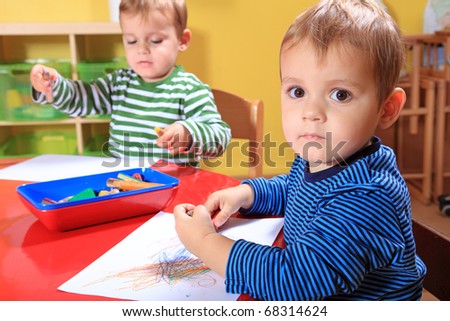 Cute european toddlers drawing a picture in kindergarten.