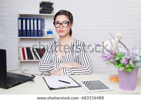 business girl in glasses sits in an Office at a computer folder paper