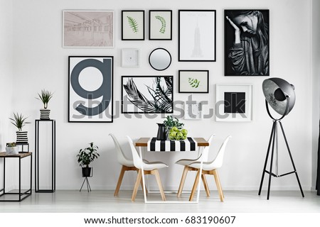 Wooden dining table with tablecloth by white wall with pictures Royalty-Free Stock Photo #683190607