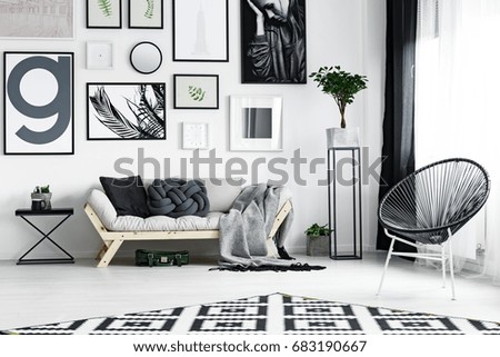Wooden white sofa with black accessories by the wall with posters