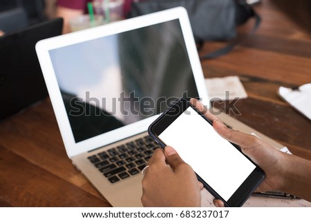 Asian woman freelancer is working on a new project on laptop computer and smart phone with blank copy space screen for your advertising text message, in soft focus at coffee shop in weekend.